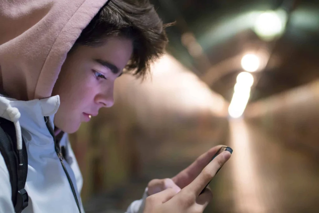 Teen staring at his phone while standing in train station