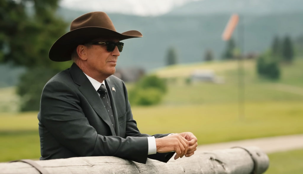 a cowboy leans against a fence - Yellowstone