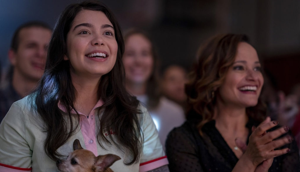 Mom and teen daughter cheer at high school game.