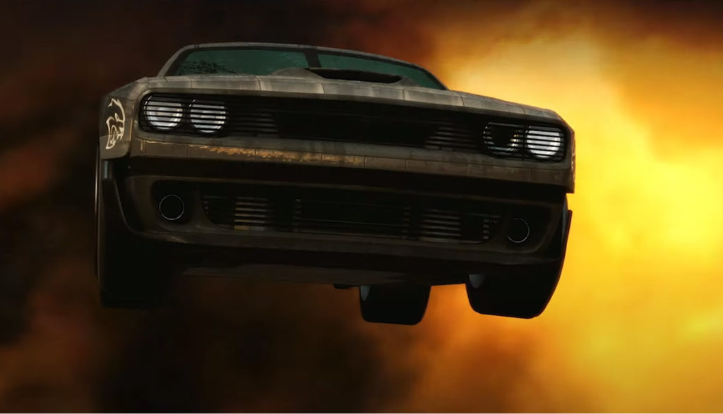 Vintage muscle car jumping through fiery explosion.