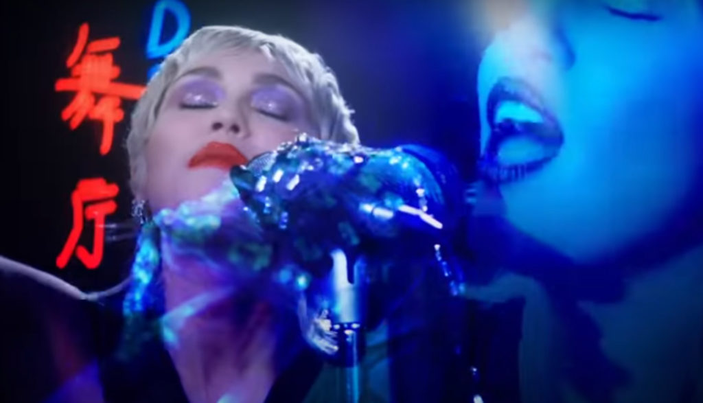 Miley Cyrus singing into mic with eyes closed