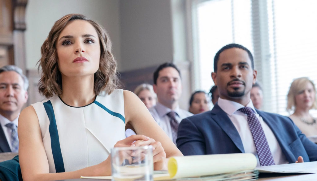 A woman and a man sit at a lawyer's desk in court.