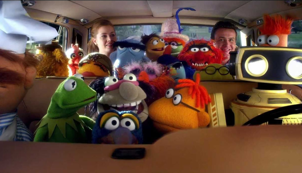 A bunch of muppets in a care with two people.