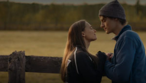 A teen guy and girl lean in to kiss.