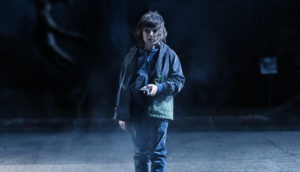 A boy with a smartphone looks scared as he walks.