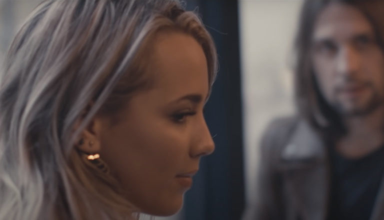 A young woman looks sideways thoughtfully while having coffee with a guy.