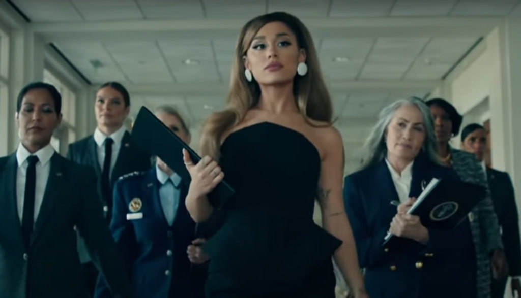 Ariana Grande as president walking down a hall in the White House with her retinue.