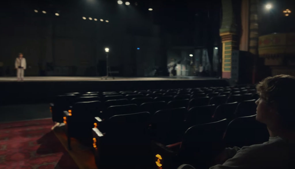 Justin Bieber watches a young actor portray him on a big stage.