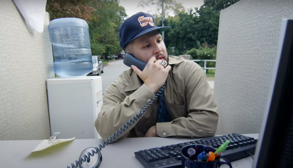 Rapper Andy Mineo sings about life's stress while sitting at a computer with a phone to his ear.