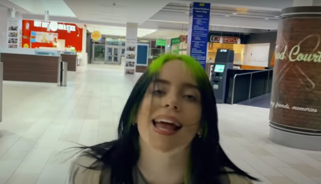 Singer Billie Eilish dances and sings in a mall.