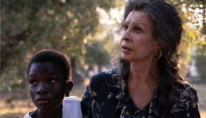 An older woman walks with a young Black child.