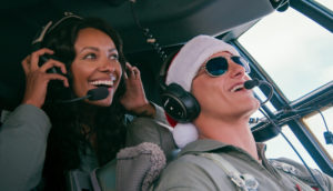A man and a woman smile in the cockpit of an airplane.