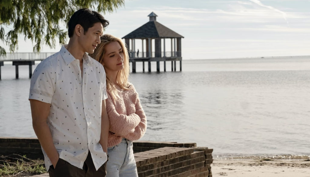 A man and woman walk arm in arm on a resort beach.