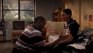 And older brother and little brother exchange a high five in the older one's dorm room.