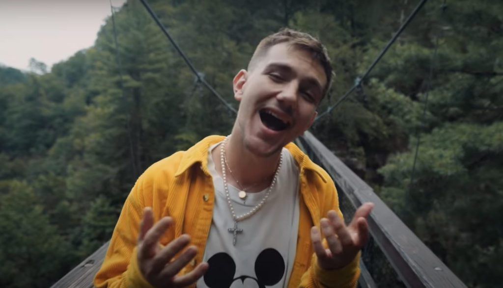 Screen shot of rapper Hulvey singing and dancing on a bridge.