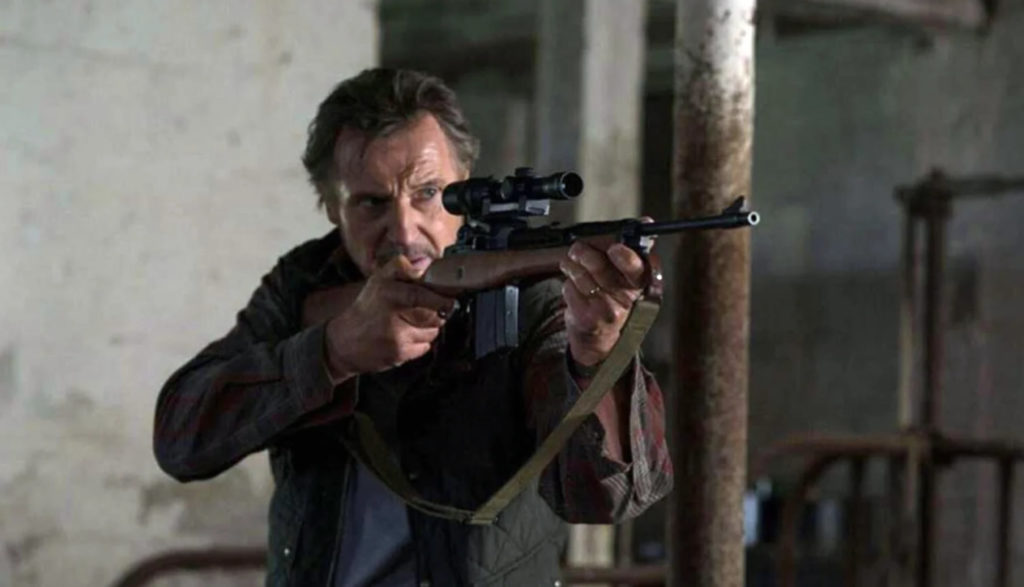 Liam Neeson shoulders a rifle and aims in The Marksman.