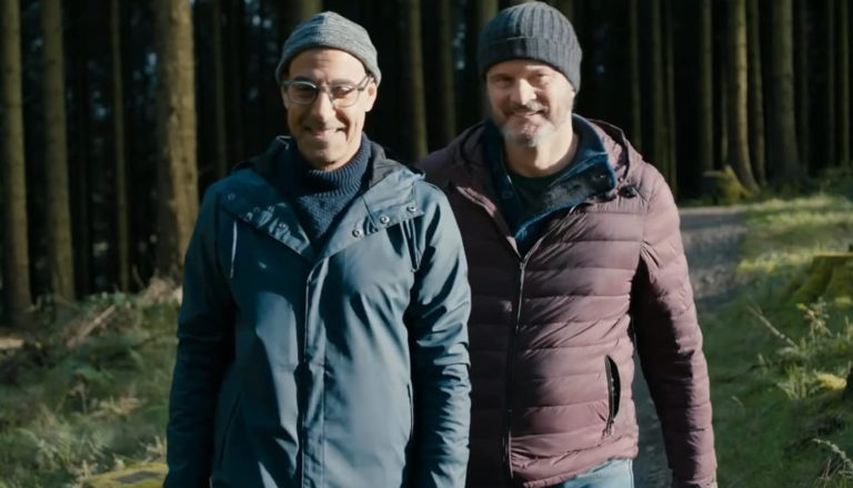 Two men walk in the woods.