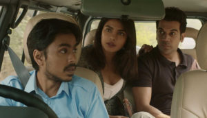 A driver in a car talks to two people in the back seat.