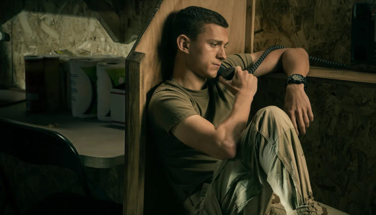 A solider sits and talks on the phone.