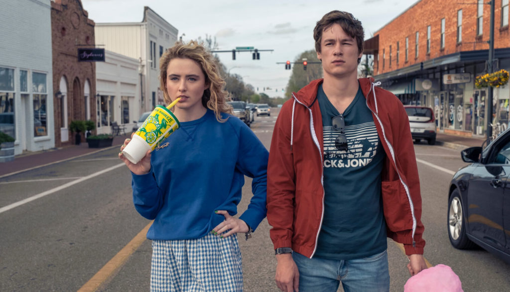 A young man and woman walk down a small-town street.