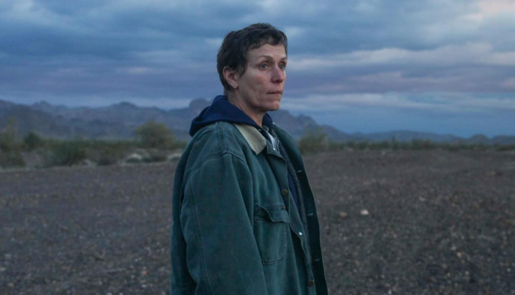 A woman stares out across a barren landscape.