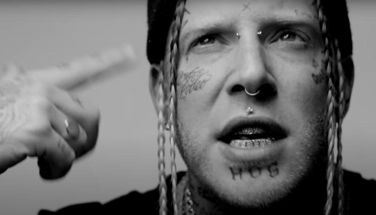 Rapper Tom MacDonald points a finger at his head and spins it.