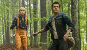 A concerned young man and woman walk through a forest.