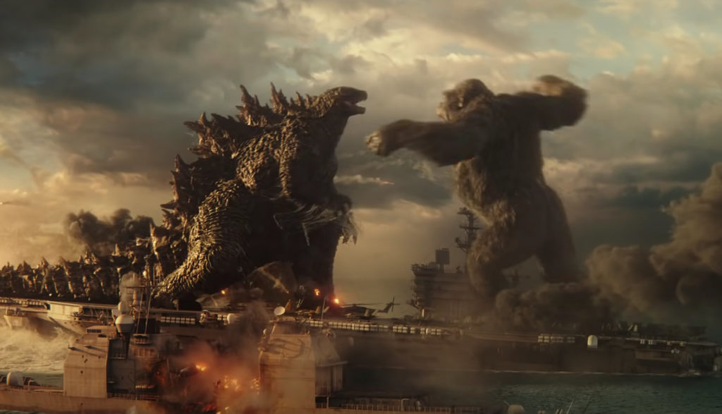 Godzilla and King Kong trade punches while standing on an aircraft carrier.