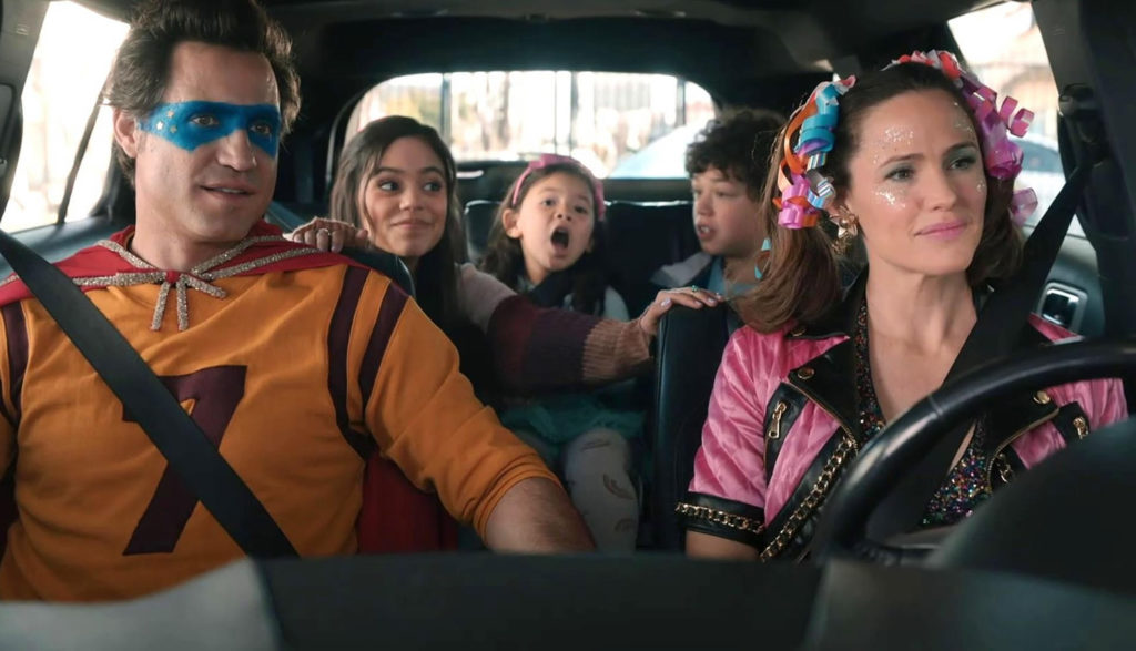 Shot from the movie Yes Day, starring Jennifer Garner, with her and her whole family in a car dressed up as superheroes.