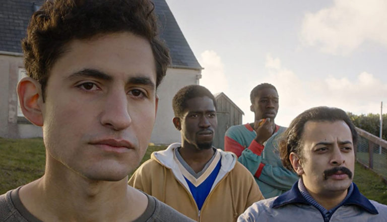 We see four men of Middle Eastern descent standing in front of a house.