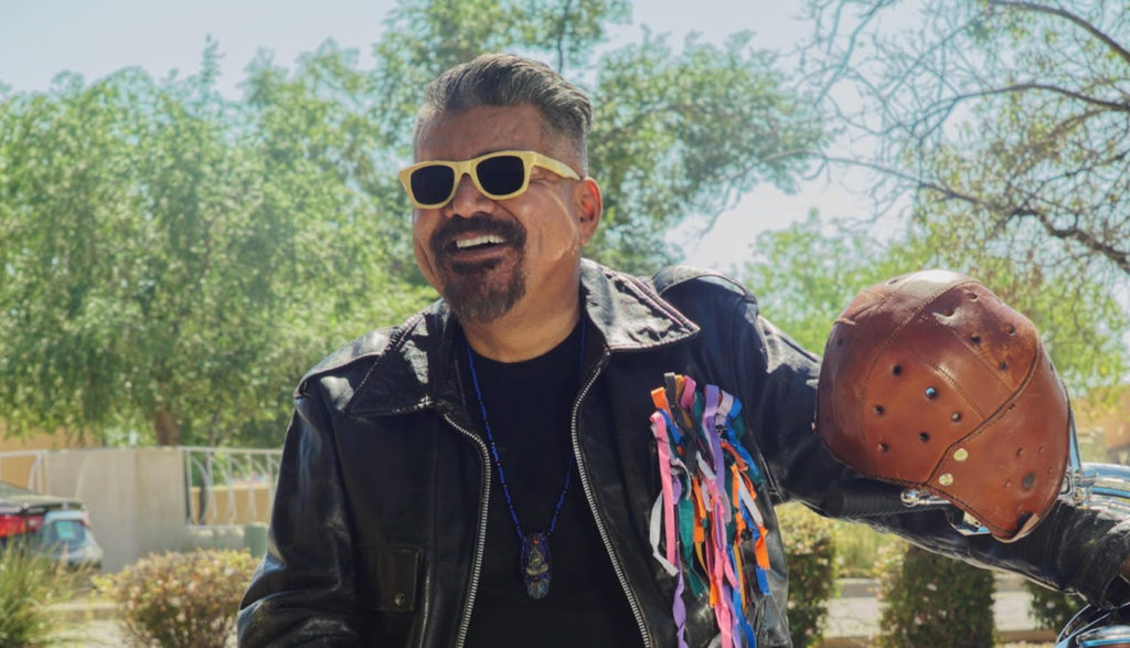 George Lopez plays an angel named Herb, and we see him here in sunglasses, leather and holding an old-school football helmet.