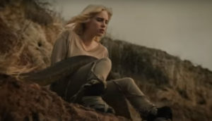 Singer Billie Eilish sits on a cliff as a python slides over her in the video for her song "Your Power."