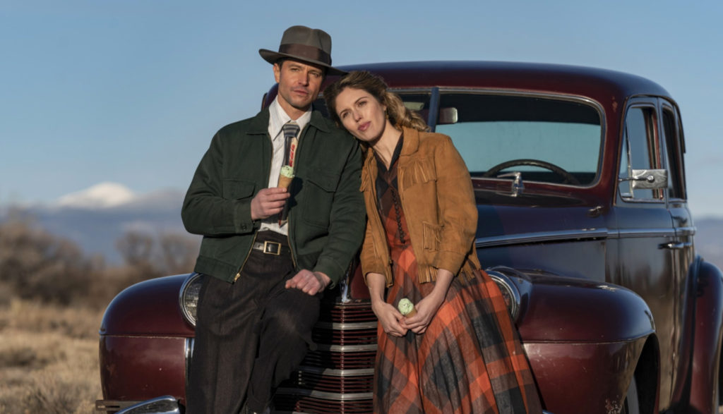 two people sitting on a car hood