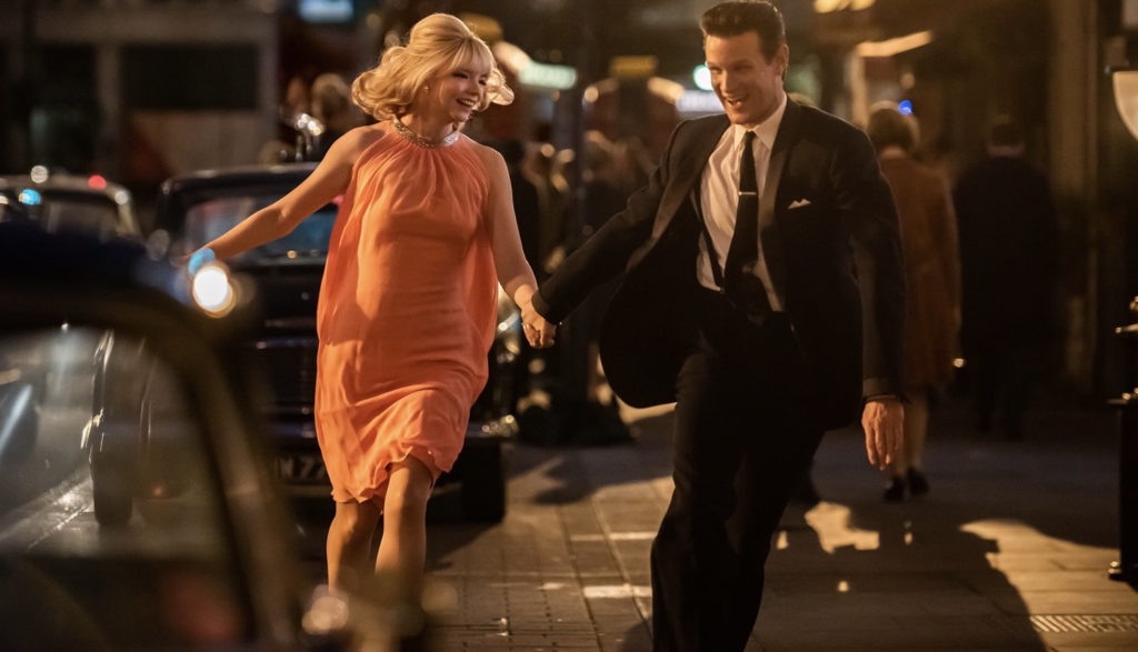 A well-dressed woman and man dance on a sidewalk.