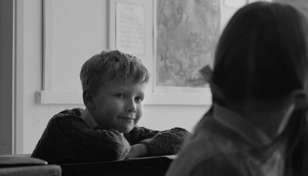 Boy grinning at a girl in Belfast movie