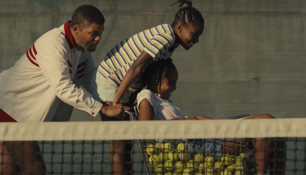 man pushing his daughters in a shopping cart full of tennis balls in King Richard