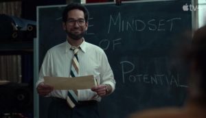 Man smiling in front of chalkboard from The Shrink Next Door tv show
