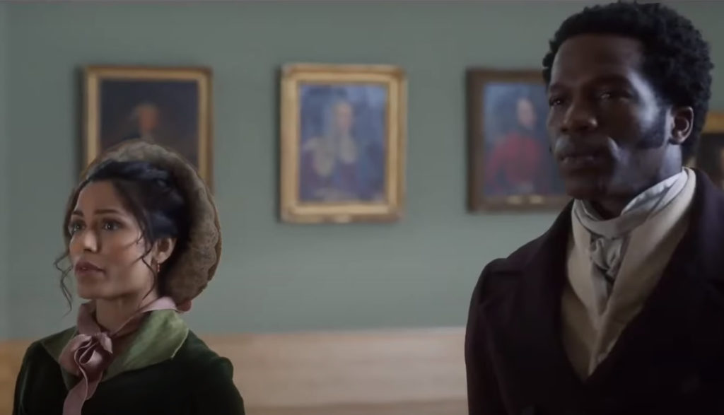 A man and woman look at paintings together in an art gallery.