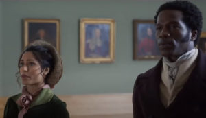 A man and woman look at paintings together in an art gallery.