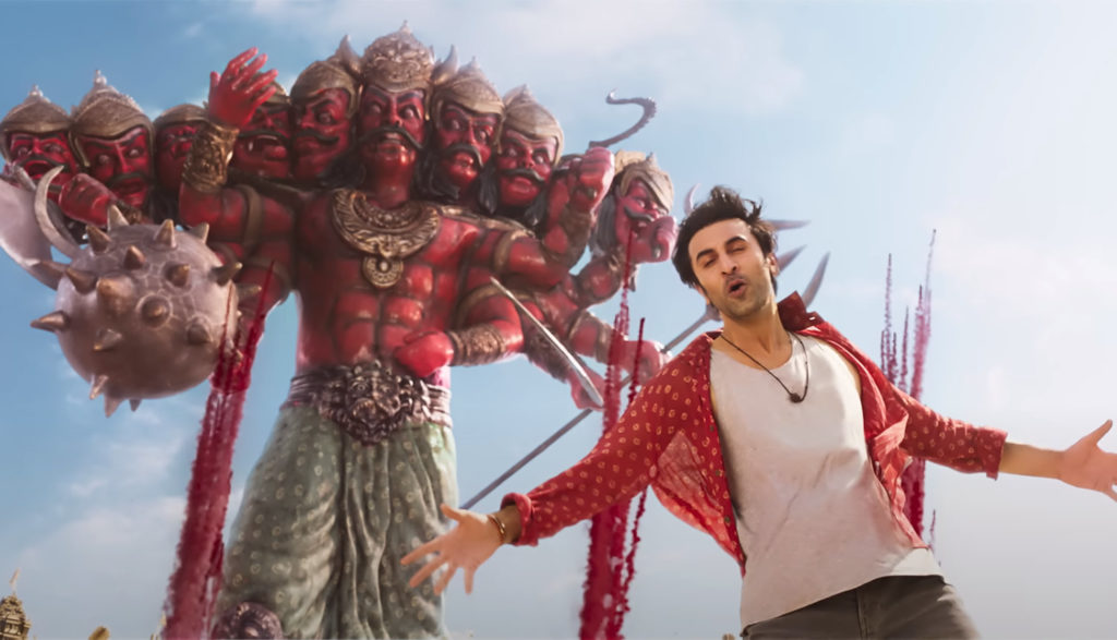 A man stands in front of a multiheaded Hindu god.