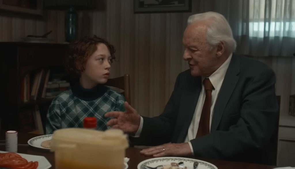 a grandfather talks to his grandson at the dinner table - Armageddon Time