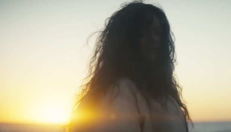 woman in a fur coat on a beach - Rihanna's "Lift Me Up" music video