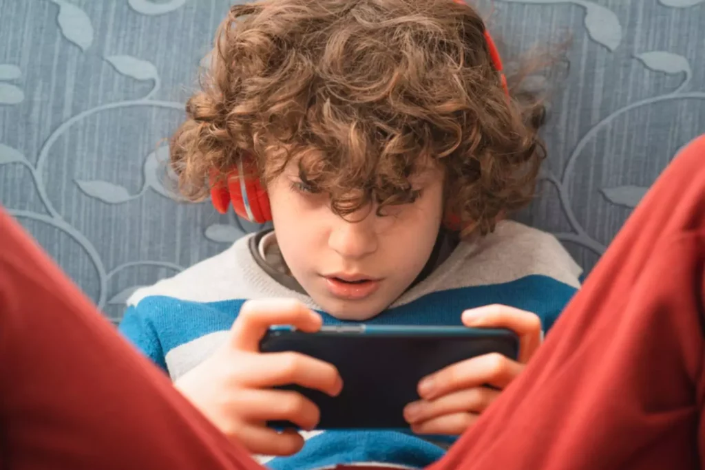 Boy engrossed in the screen on his phone|